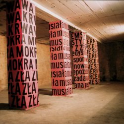 4 KOLUMNY , 2001, wydruki naklejone na kolumnach: wys.280cm, bok 70cm. Napisy: KRWAWA MOKRA ZŁA MUSIAŁA Z ZEMSTY NIEDYSPONOWANA NIEPOŻĄDANA WIERNE PSIE SERCE. Wystawa zbiorowa „Maskarady” Centrum Sztuki Współczesnej Inner Spaces, Poznań