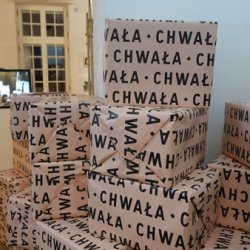 Chwała, instalacja tekstowa; papier pakunkowy,  druk cyfrowy, opakowane 30 kartonów z obciążeniem, wystawa Świat poszedł do przodu, a nóżki zostały na swoim miejscu, galeria 18A, Warszawa, 2018