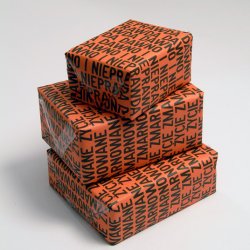 Pudełka opakowane w papier z nadrukiem “Życie zmarnowane” i „Dawno i nieprawda”